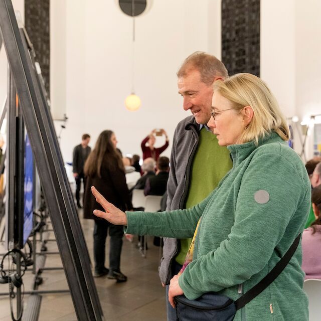 Blick in die Ausstellung „Kirchen als Vierte Orte – Perspektiven des Wandels“ in der Berger Kirche Düsseldorf. Besucher*innen erleben die Videointerviews und Beispiele neuer Nutzungskonzepte leerstehender Kirchen in Nordrhein-Westfalen.